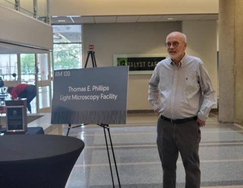 Dr. Tom Phillips next to new sign for facility named in his honor
