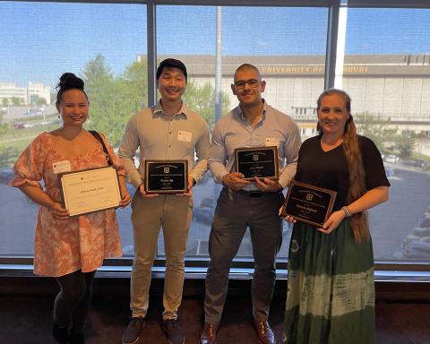 The image shows the four award winners, posing as a group with their respective awards in hand.